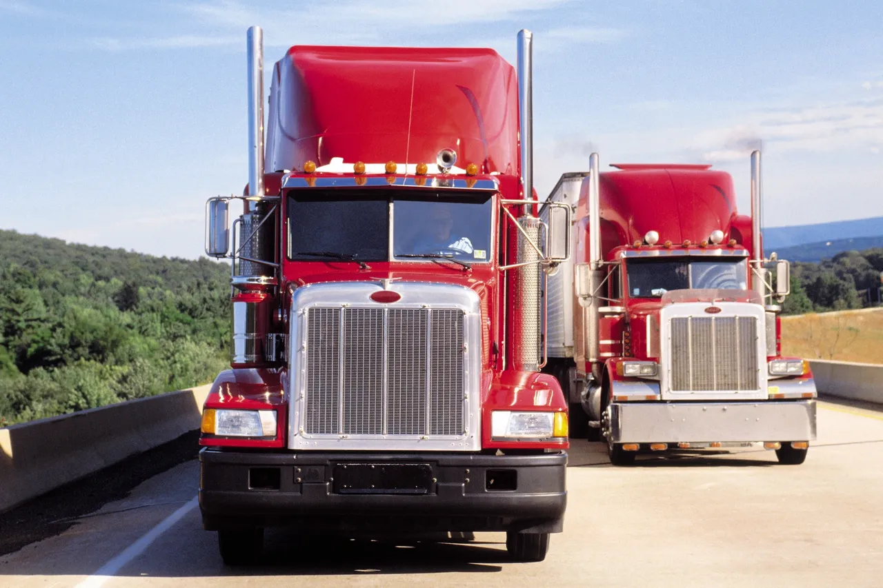 Two red semi-trucks driving on a highway.