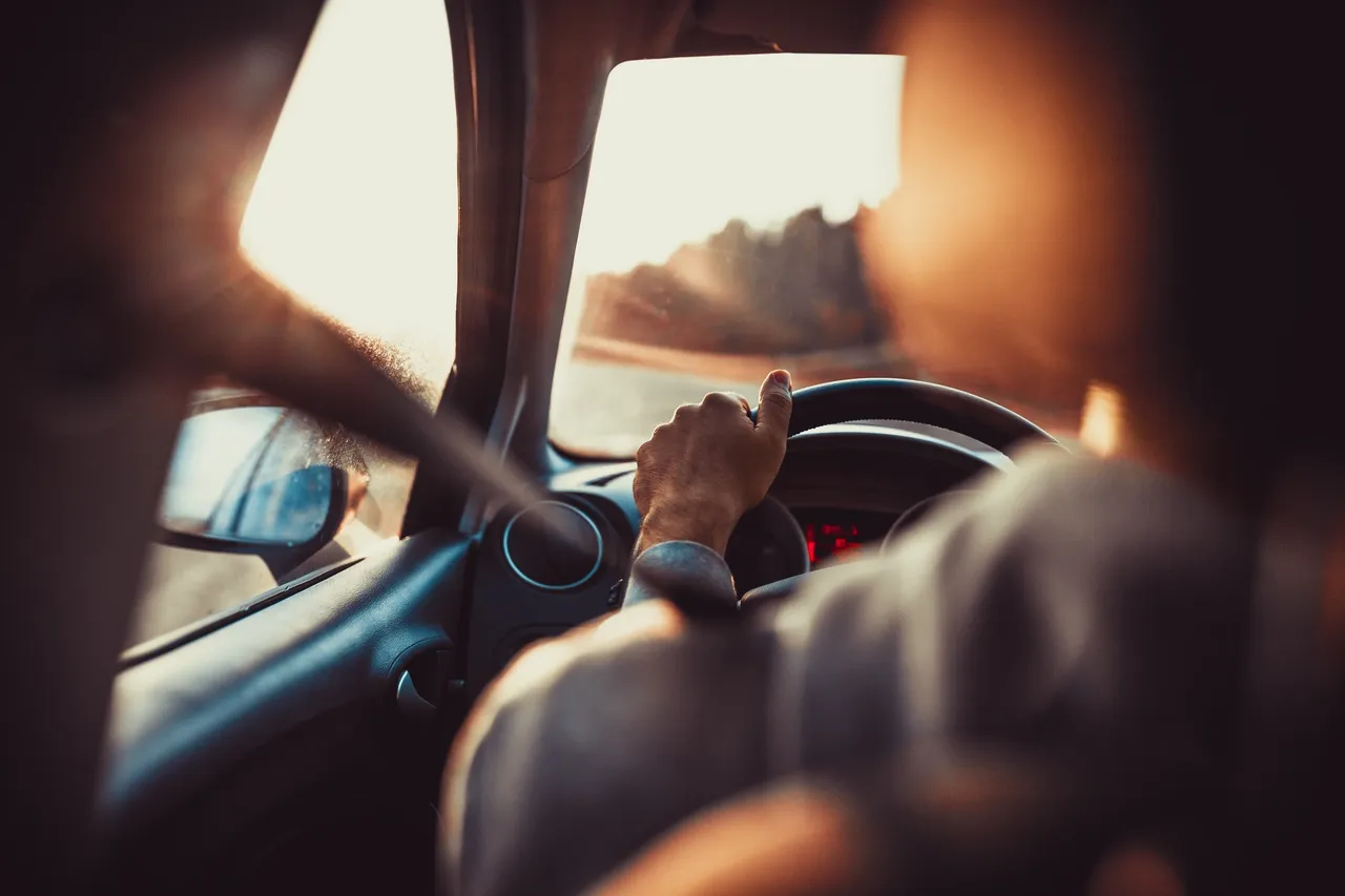 Person driving a car with sunlight streaming through the window.