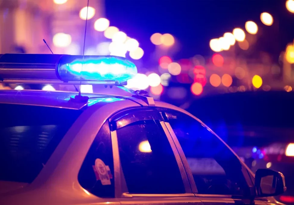 A police car with flashing blue lights at night.