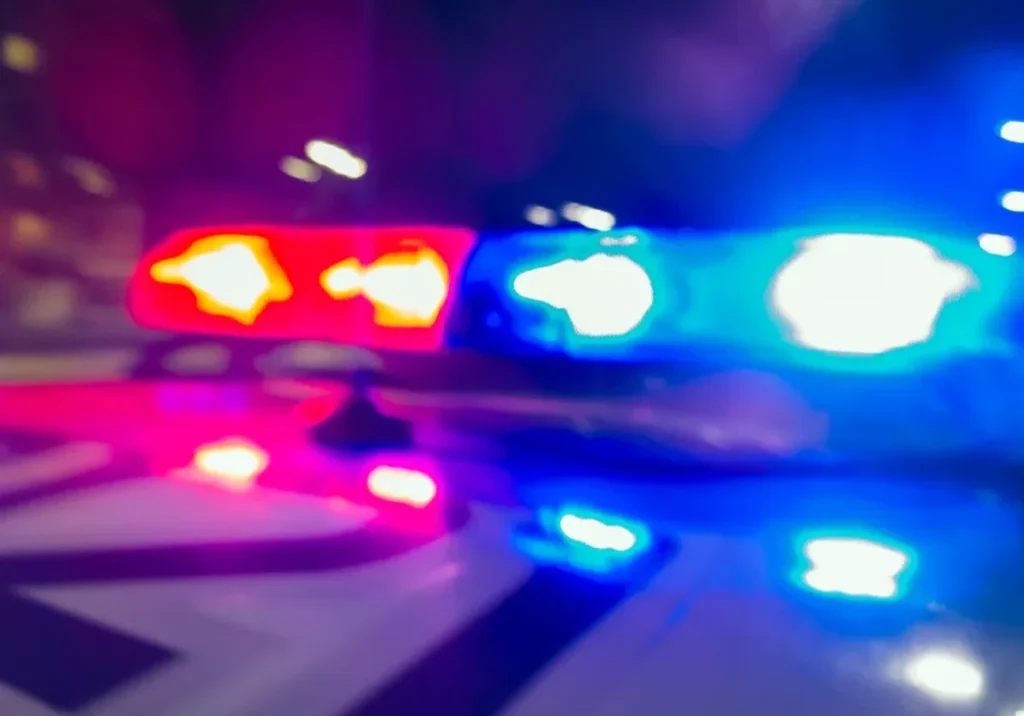 Blurred police car lights flashing red and blue at night.