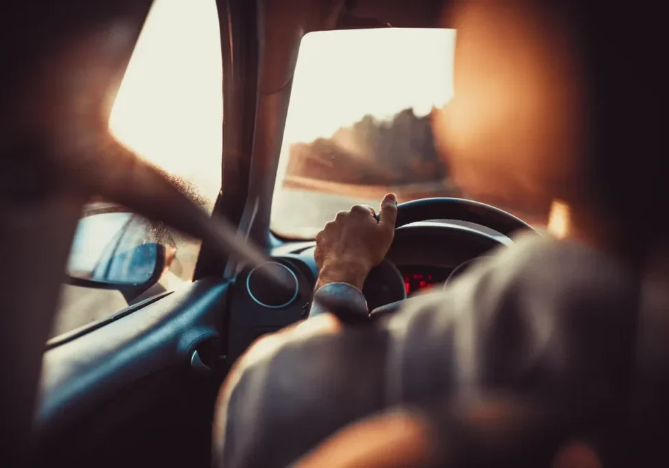 Person driving a car with sunlight streaming through the window.
