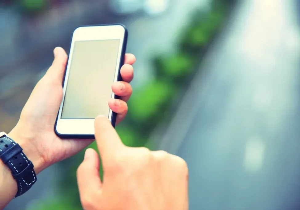 A person holding and using a smartphone with a blank screen.